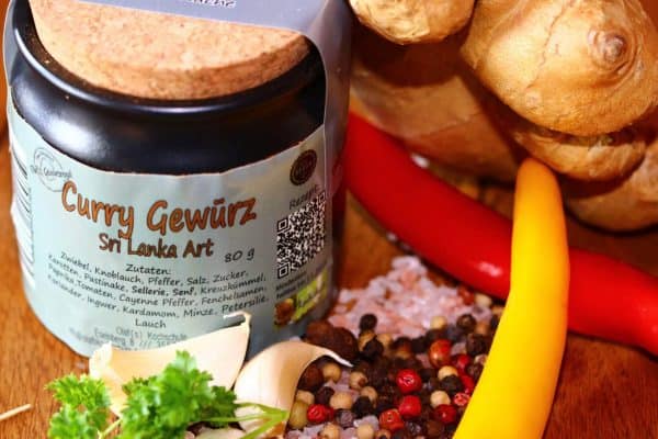 Gewürzregal mit Gewürzgläsern, Paprika, Knoblauch und Pfefferkörnern.