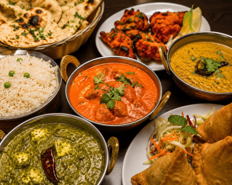 Vielfalt indischer Gerichte bei TAJ im Taunus, inklusive Curry, Naan und Samosas.